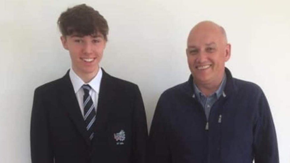 Lewis pictured in his school uniform with his dad, Ian McCracken