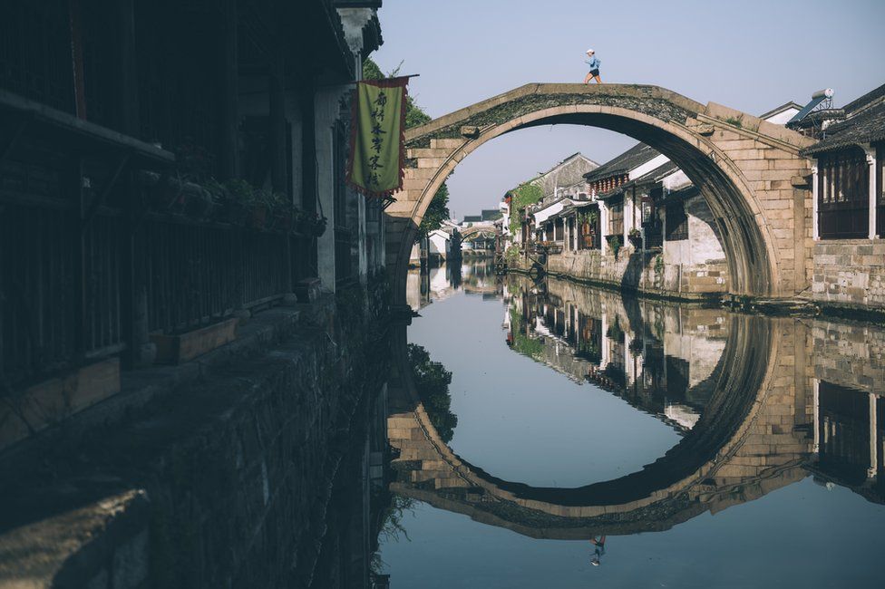 Mina Guli crosses a bridge over a water canal in Nanxun, China