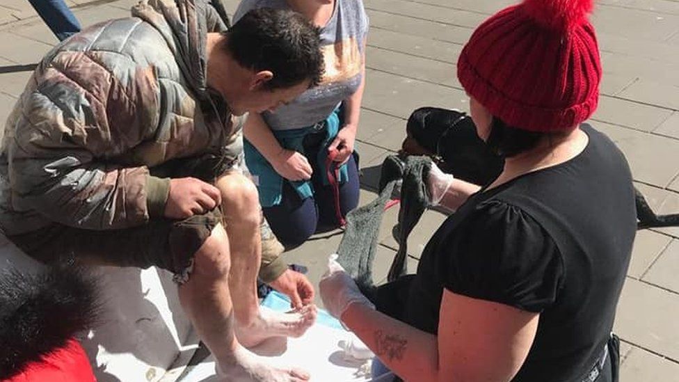 A homeless man has his feet examined by volunteers for Homeless Help
