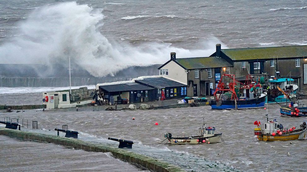 Waves crash over the sea wall at the harbour in Lyme Regis in Dorset as Storm Eunice hits the south coast on 18 February 2022