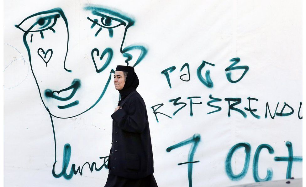 A Romanian Orthodox nun passes by a graffiti symbolizing the crying face of a LGBT community member on 5 Oct
