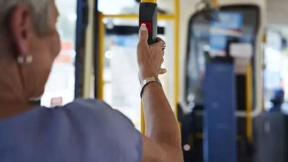 A woman presses the bell on a bus to get off at the next stop