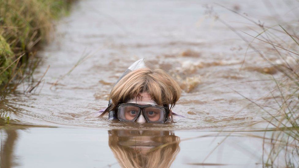 Woman in goggles and snorkel is partly submerged with only her head showing above the water