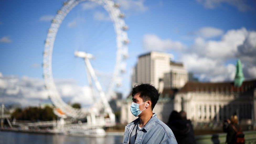 A man wearing a protective face mask walks across Westminster bridge