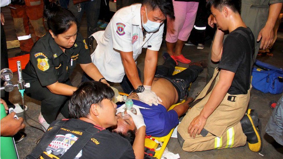 Rescue workers aid a victim after an accident, possibly caused by a fire retardant chemical according to the bank, at the headquarters of Thailand's Siam Commercial Bank in Bangkok 13 March 2016