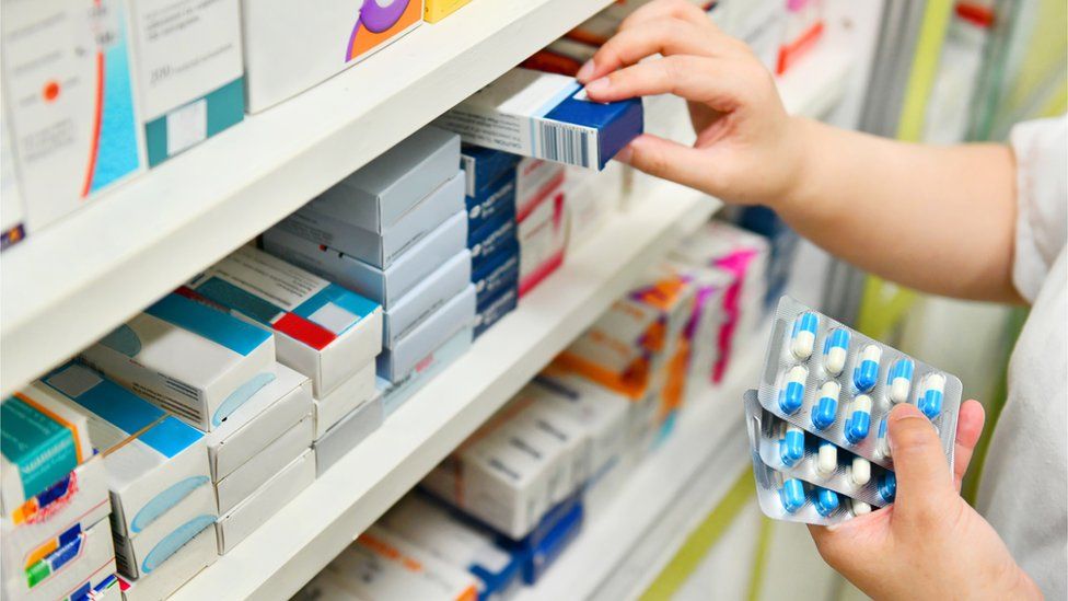 Pharmacist taking drugs from shelves