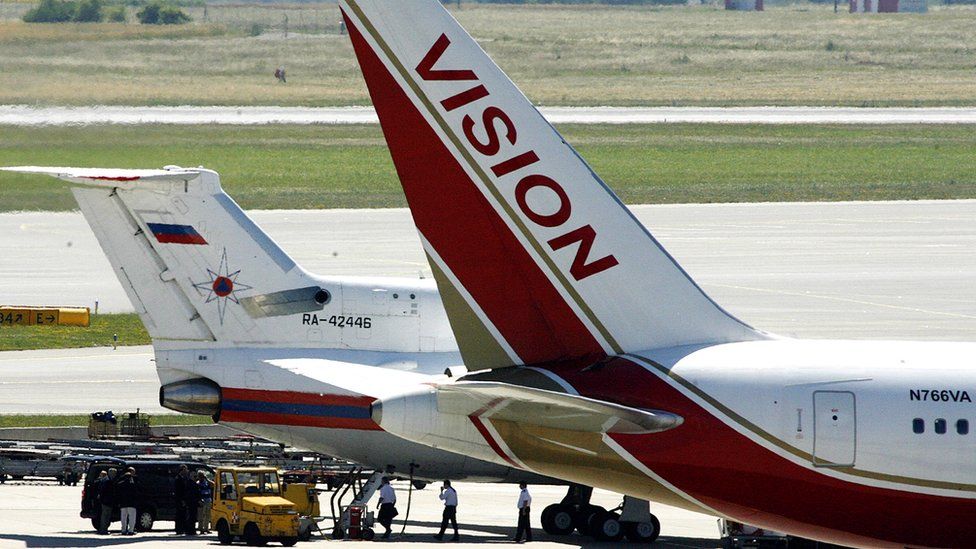 Unidentified officials stand by a Russian emergency situations ministry plane that sits next to a Vision airlines plane presumed to be carrying 10 men and women who worked as Russian spies in the United States at Vienna airport on July 9, 2010 in Vienna