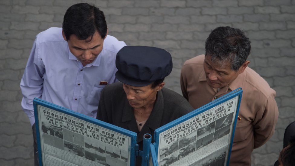 North Korean men read a newspaper in the street in Pyongyang (file image)