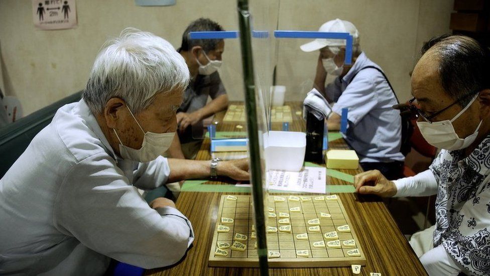 Elderly Japanese men play a board game during Covid
