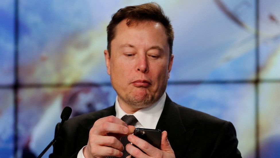 SpaceX founder and chief engineer Elon Musk looks at his mobile phone during a post-launch news conference to discuss the SpaceX Crew Dragon astronaut capsule in-flight abort test at the Kennedy Space Center.