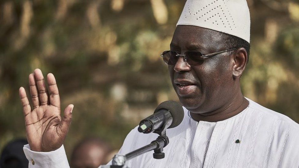 President Macky Sall greets the crowd as he speaks to the media after casting his vote