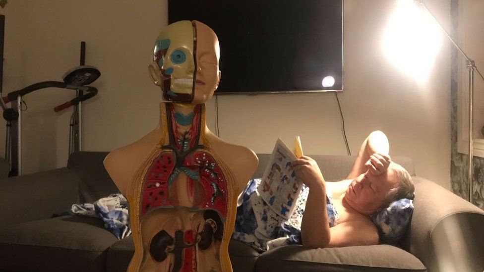 Man sleeping in a loft with an anatomy doll