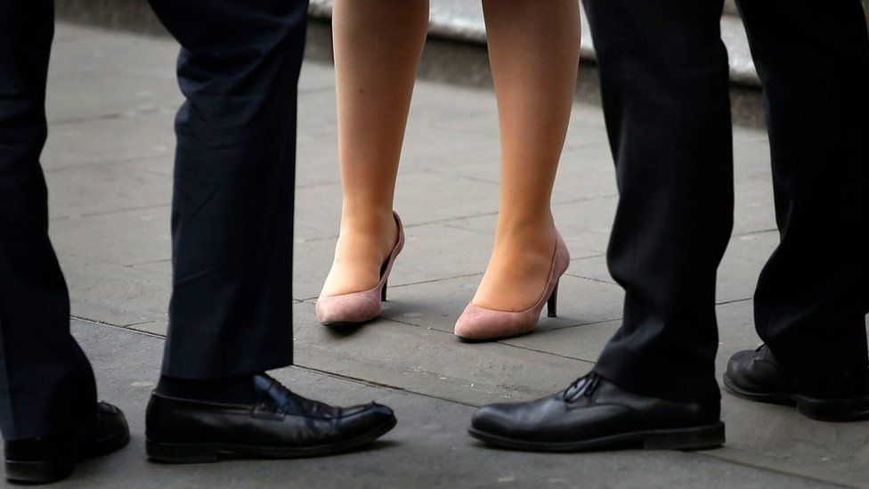 The legs of two men and a women in business attire
