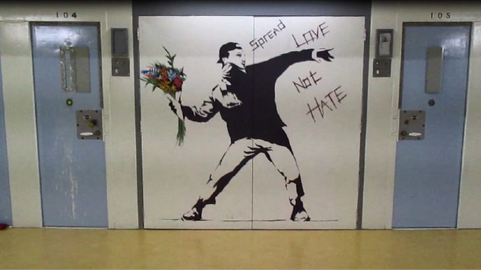 A mural on an interior prison wall - a copy of the Banksy picture of a youth throwing flowers