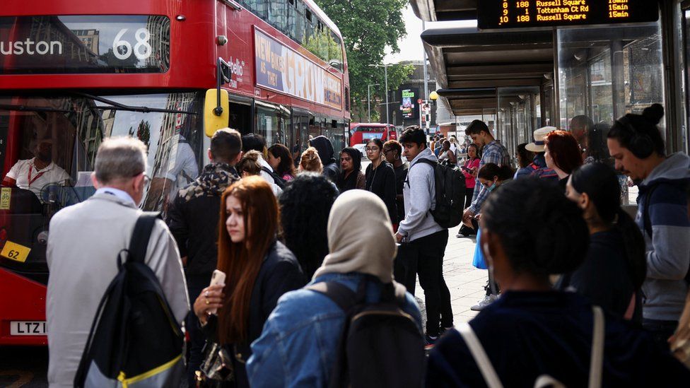 Passengers queue for a bus outside the Waterloo Station, on the first day of national rail strike in London