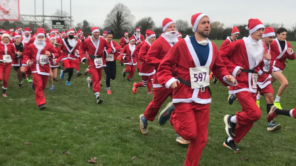 A group of people running in Santa costumes