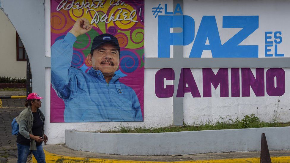 Женщина идет перед рекламным щитом с изображением президента Никарагуа Даниэля Ортеги