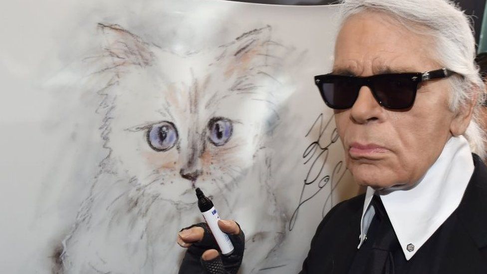 Lagerfeld posing with a painting of his cat