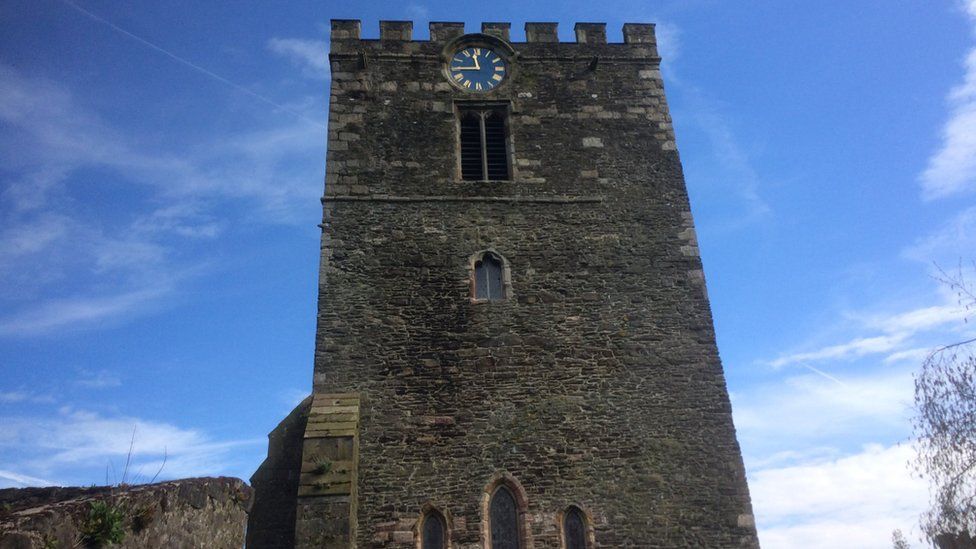 The clock stands at the top of the 12th Century St Mary's church