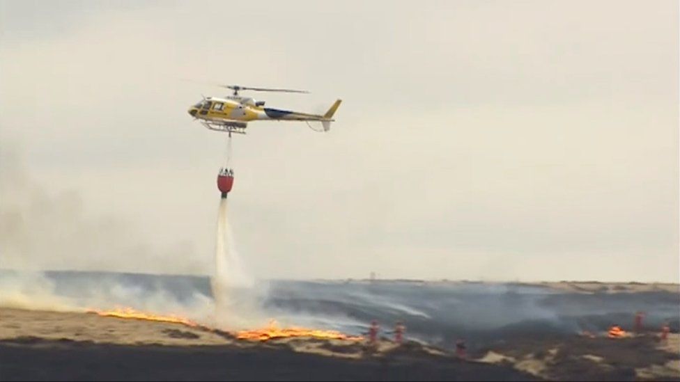 A helicopter drops water onto the fire