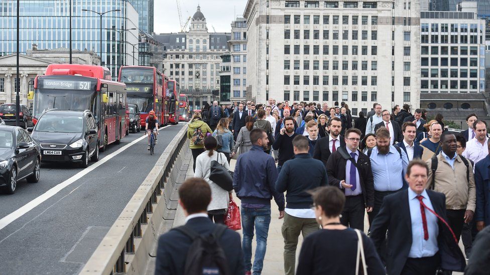 Commuters walk across London Bridge