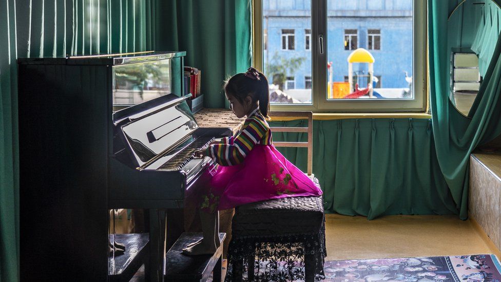 Girl in traditional dress plays the piano