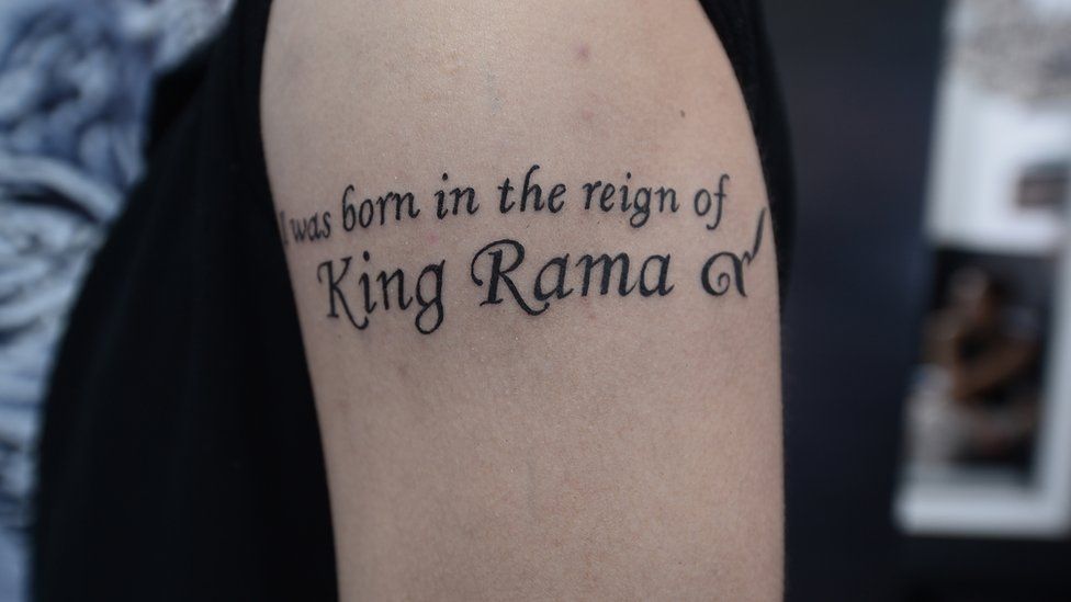 Tattoo reads in English: "I was born in the reign of King Rama" with the Thai number 9