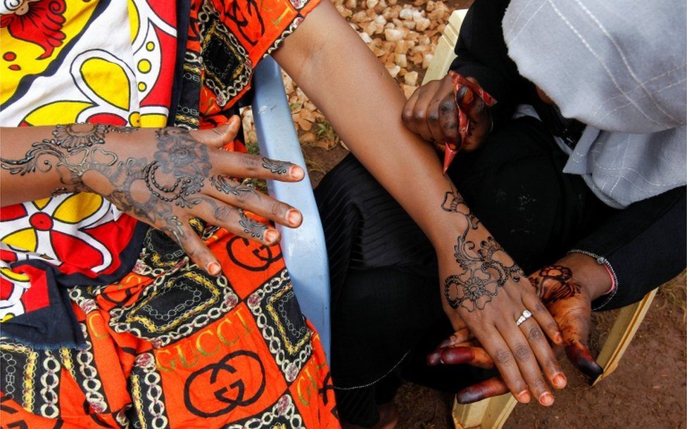 Muslim women apply henna to each others' hands after prayers.