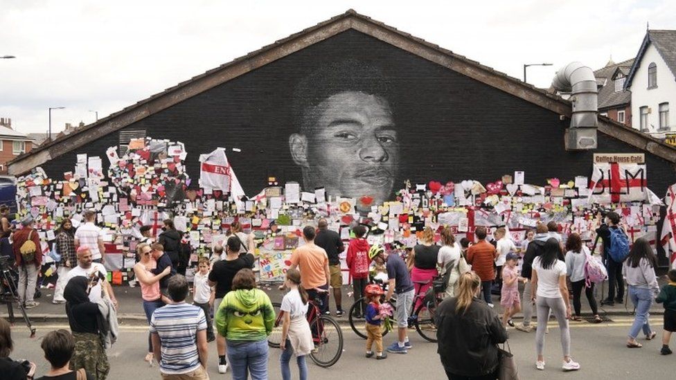 Crowd viewing messages of support on the Marcus Rashford mural