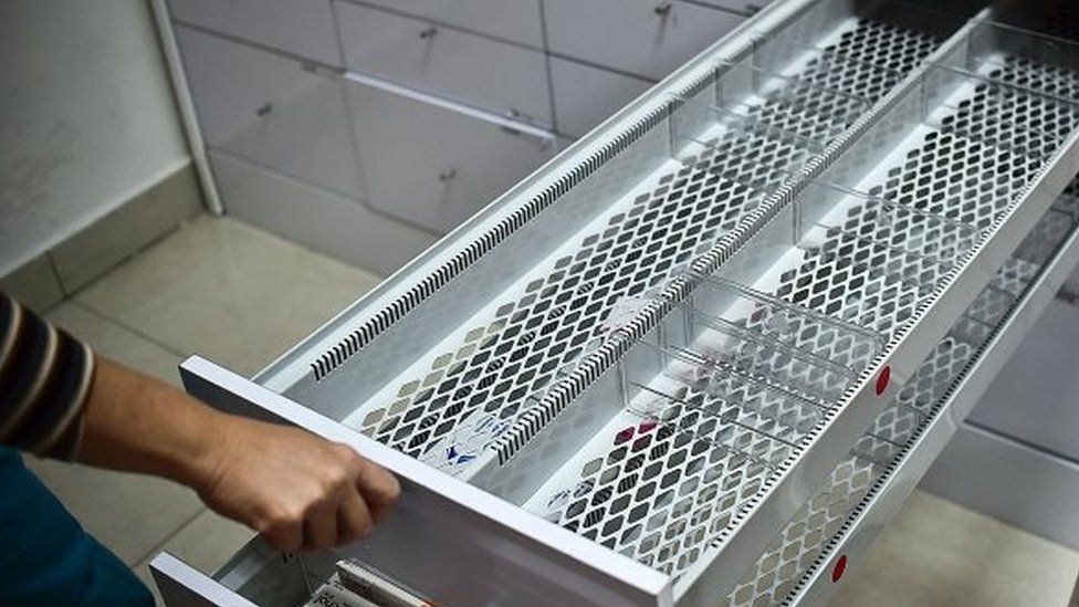 A worker of a pharmacy opens an empty drawer in Caracas on May 30, 2016.