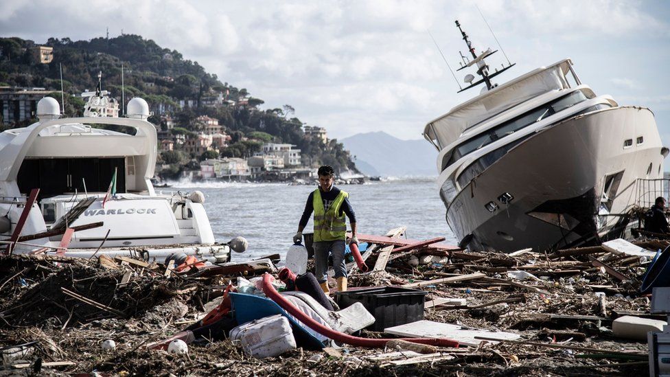 A man walks through garbage between two yachts after a storm hit the harbour and destroyed a part of the dam during the last night on October 30, 2018