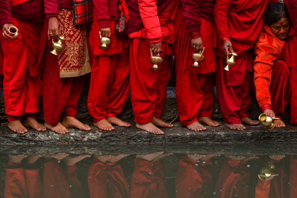 People wait to fill pots with water from the Bagmati River at the Pashupatinath Temple during the month-long Swasthani festival in Kathmandu
