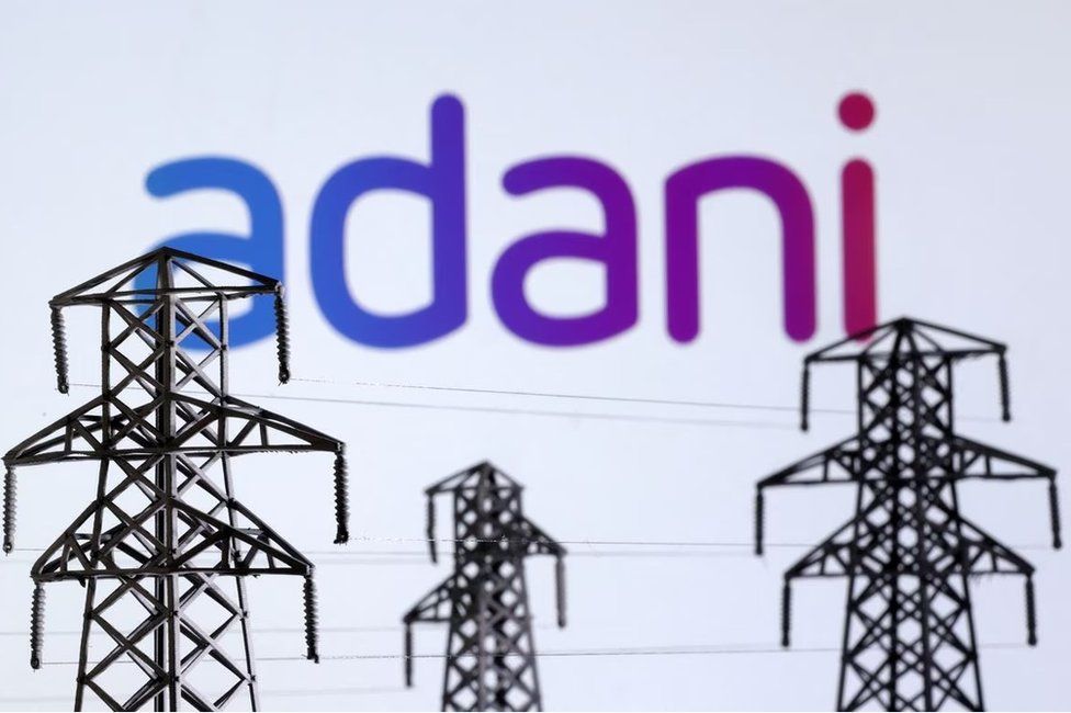Electric power transmission pylon miniatures and Adani Green Energy logo are seen in this illustration taken, December 9, 2022