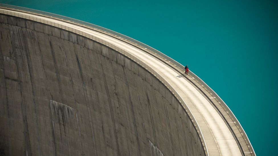 Two people standing on the edge of a dam