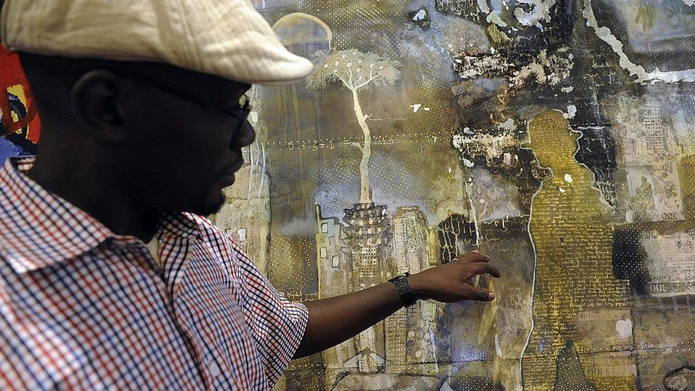 Kenyan painter Paul Oditi looks at his work displayed for the first commercial auction of east African art on November 4, 2013 in Nairobi, on the eve of the the auction.