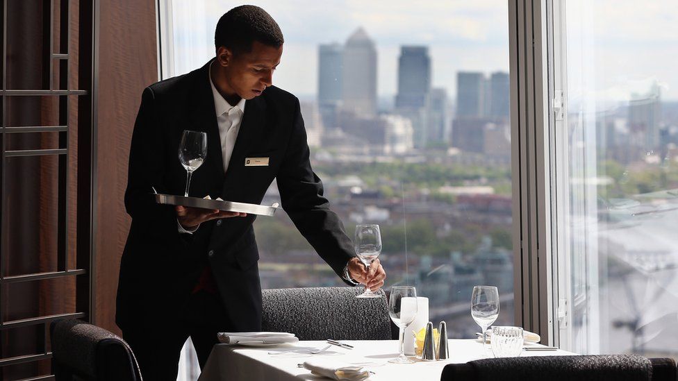 A waiter lays out glasses on a table