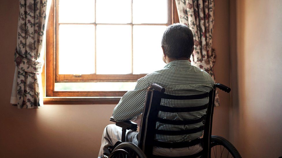 Man in a wheelchair looking out of a window