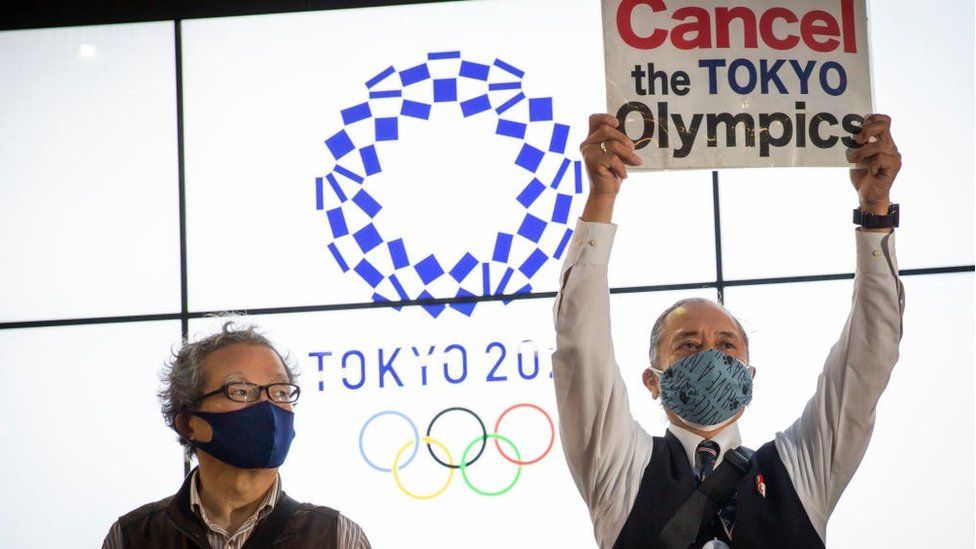 Протестующий держит плакат во время акции протеста против Олимпийских игр в Токио 17 мая 2021 года в Токио, Япония