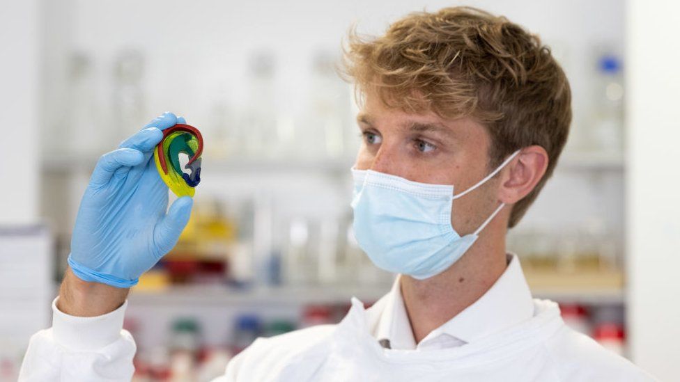 Trainee plastic surgeon Tom Jovic holds a 3D printed ear which has been created in the lab