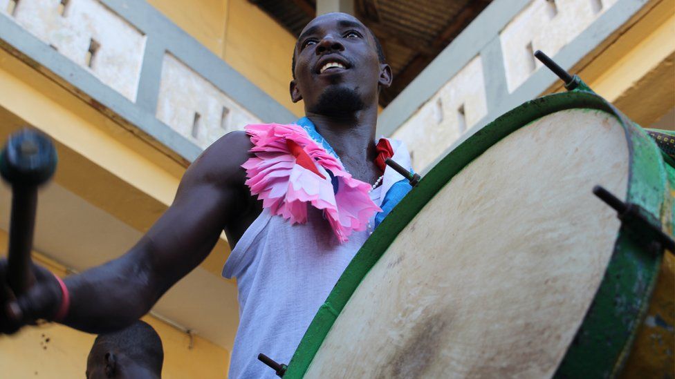 Man prepares to hit a drum hanging vertically from his shoulder in Sekondi Ghana