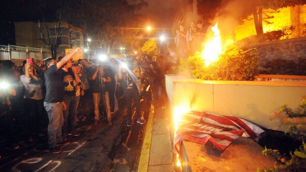 Protesters burn the US flag during a march in support of the caravan of migrants, in Tegucigalpa, Honduras