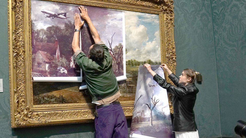 Two protesters attach their own version of the painting