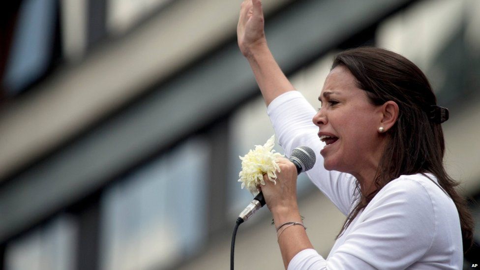 Opposition leader Maria Corina Machado holds a white flower as speaks during an anti-government protest in Caracas, Venezuela, Saturday, May 30, 2015