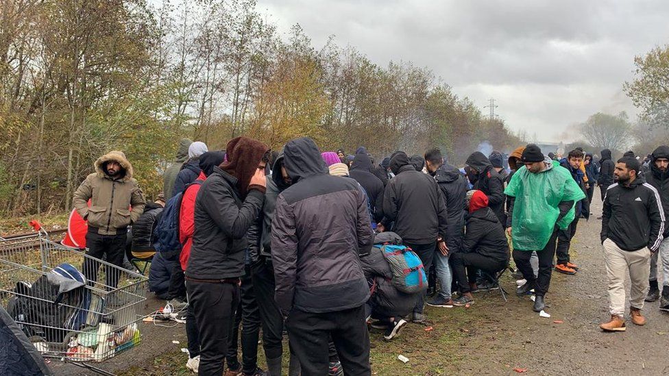 People walk around at a migrant camp in northern France