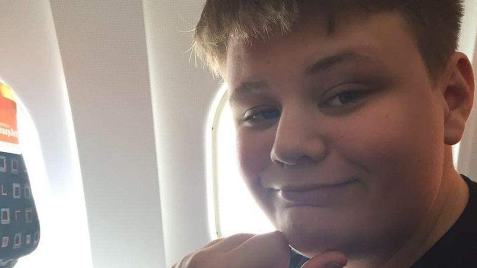 Teenager smiling from what appears to be a seat on an aircraft