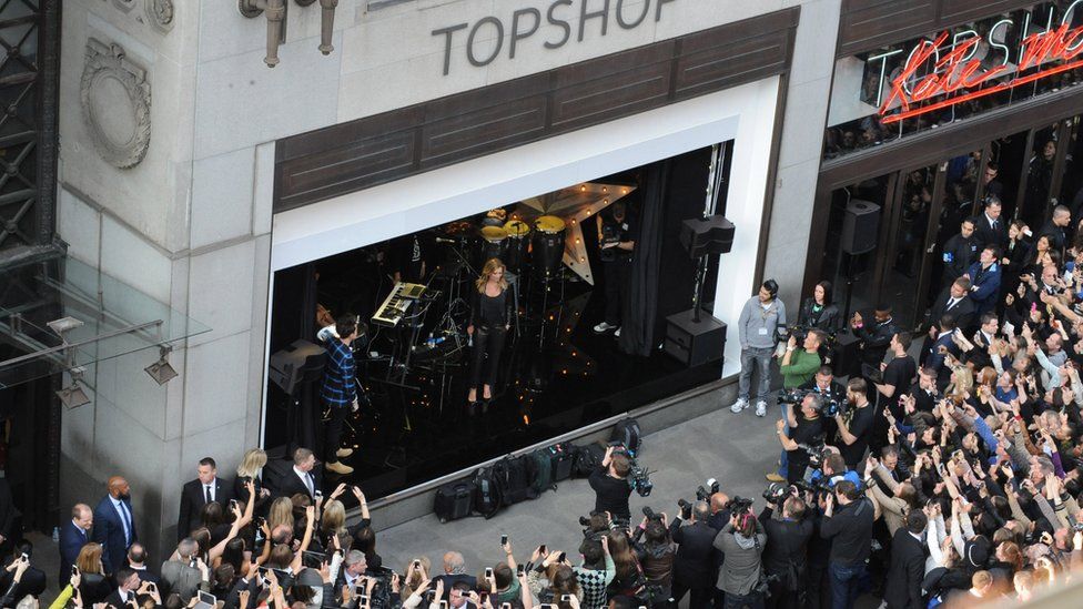 Kate Moss stands in a window of Topshop in 2014