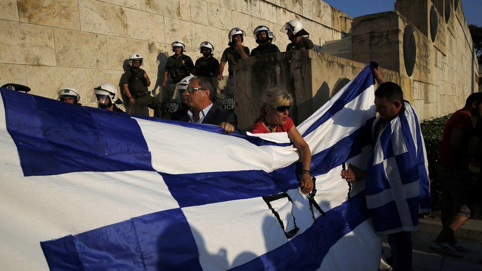 Protesters hold a Greek flag in front of the parliament building during an anti-austerity rally in Athens