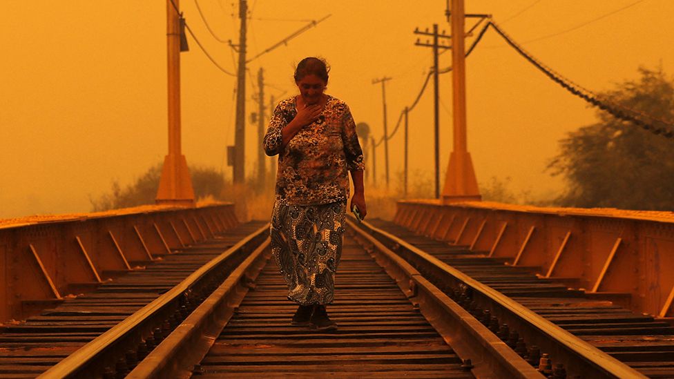 A woman walks on a bridge during the fires in Renaico, Araucania region, Chile on February 4, 2023