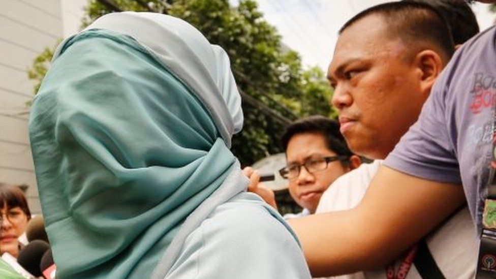 Former Mayor of Saguiran, Lanao del Sur, Rasmiya Macabgaos (left), allegedly involved in the illegal drug trade covers her face in her hijab after surrendering at Camp Crame, Quezon City (07 August 2016)