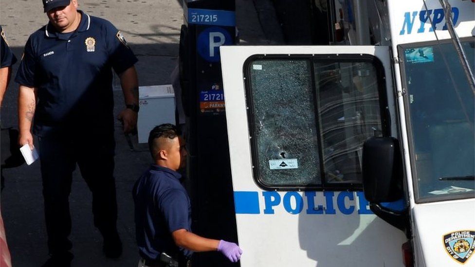 New York City Police Department (NYPD) investigators work near a police vehicle where a gunman fatally shot a female New York City police officer.